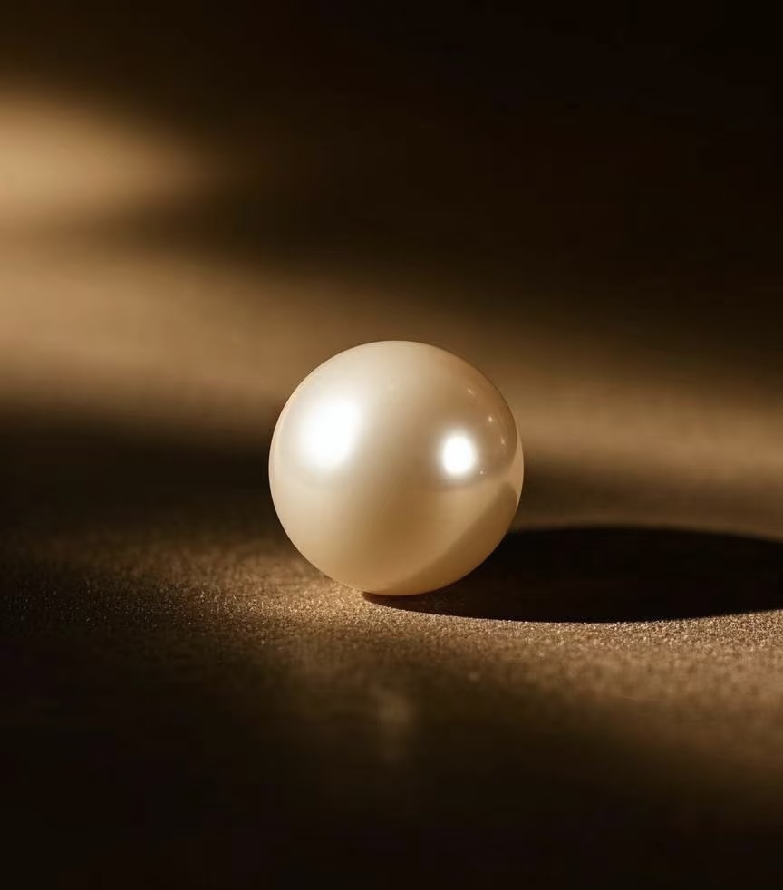 A single luminous pearl resting on dark silk